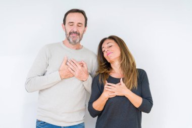 Güzel orta yaş kaç sevgi ile gülümseyen izole arka plan üzerinde içinde kapalı gözler ve yüzünde minnettar jest ile göğüs üzerinde eller. Sağlık kavramı.