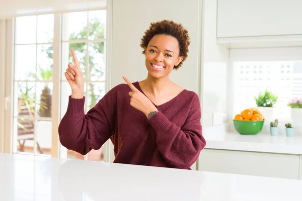 年轻美丽的非洲裔美国女人在家里微笑着 看着相机指向用两只手和手指的一侧 — 图库照片