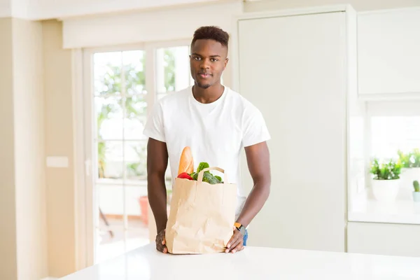 Afroamerický Muž Držící Papírový Pytel Plný Čerstvých Potravin Sebevědomým Výrazem — Stock fotografie