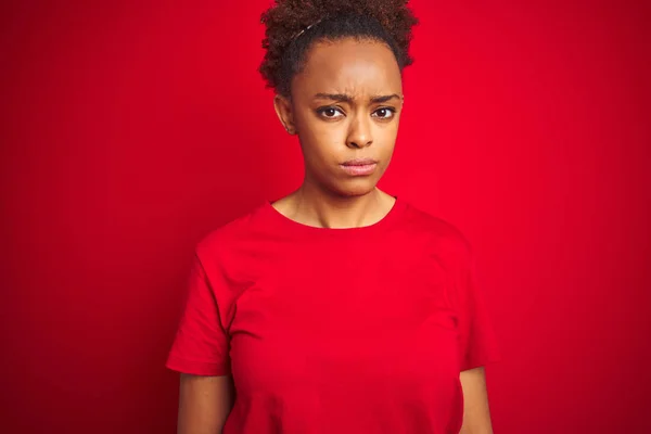 孤立した赤い背景の上にアフロ髪を持つ若い美しいアフリカ系アメリカ人女性は懐疑的で神経質で 問題のために動揺しています 否定的な人 — ストック写真