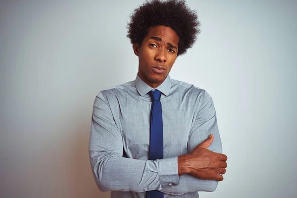 American business man with afro hair wearing shirt and tie over isolated white background skeptic and nervous, disapproving expression on face with crossed arms. Negative person.