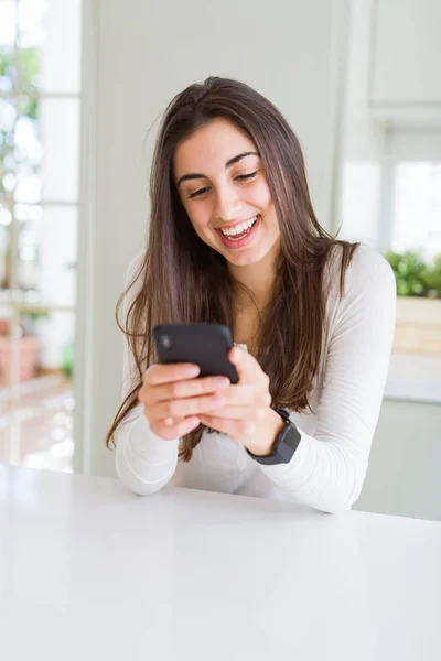 Ung kvinna som använder smartphone, leende glatt textning och skriva — Stockfoto