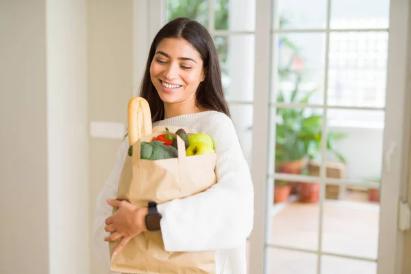 Mooie jonge vrouw glimlachend een papieren zak vol vers — Stockfoto