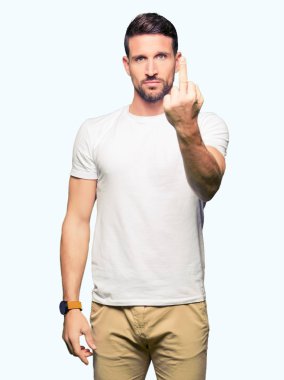 Rahat beyaz t-shirt giyen yakışıklı adam orta parmak, kabalık ve kaba Fuck Out ifade gösteren