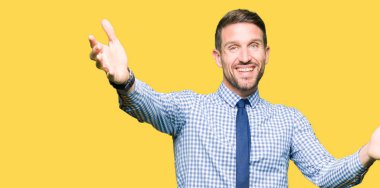 Yakışıklı iş adamı sarılmak için açık kollar ile gülümseyen kamera bakarak kravat giyiyor. Mutluluğu kucaklayan neşeli ifade.