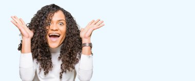 Kıvırcık saçlı deli ve silah ile başarı için hayran Balıkçı Yaka Kazak kutluyor giyen genç güzel kadın kaldırdı ve açık gözleri çığlık heyecanlı. Kazanan kavramı