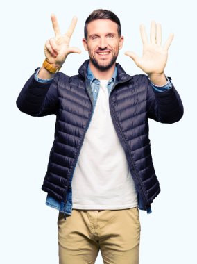 Kış ceket gösterme ve parmakları ile işaret giyen yakışıklı adam kendinden emin ve mutlu gülümseyerek süre sekiz numara.