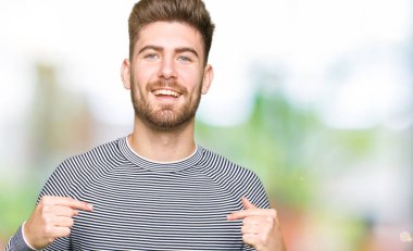 Yüzünde gülümseme ile kendinden emin görünüyorsun, kendini gururlu ve mutlu parmakları ile işaret çizgili süveter giyen genç yakışıklı adam.