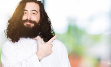 Neşeli bir gülümseme ile el ve parmak kadar yan yüzünde mutlu ve doğal ifade ile işaret yüz ile İsa Mesih giyinen adam