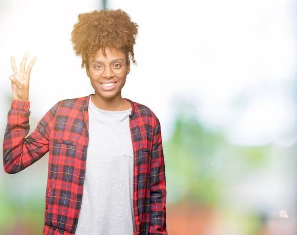 Güzel genç Afro-Amerikan kadın gözlük gösterilen ve parmakları ile işaret izole arka plan üzerinde ise kendinden emin ve mutlu gülümseyerek üçüncüsü.