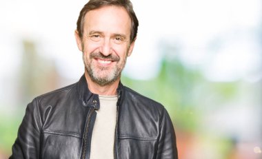 Siyah deri giyen orta yaş yakışıklı adam ceket el ele tutusun ve rahat ve neşeli gülümseyen parmak çarpı işareti. Başarı ve iyimser