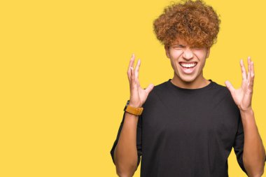 Afro saçlı genç yakışıklı adam siyah t-shirt deli giyen ve deli bağırarak ve agresif ifade ve kollar kaldırdı ile bağırıyor. Hayal kırıklığı kavramı.