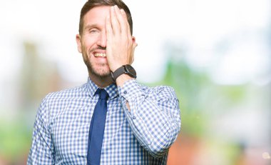 El yüz ve sürpriz duygu kendinden emin gülümseme ile tek gözüyle kapsayan kravat takan yakışıklı iş adamı.