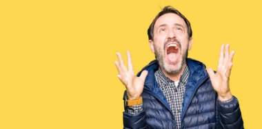 Orta yaş yakışıklı adam deli ve deli bağırarak ve agresif ifade ve silah kaldırdı bağırıyor bir kış palto giyiyor. Hayal kırıklığı kavramı.