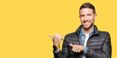 Yakışıklı adam giyen kış ceket arkasından el ve kadar başparmak ile işaret emin gülümseyen