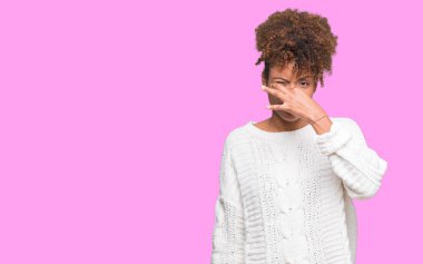 İzole arka plan kokulu üzerinde kış kazak pis ve iğrenç bir şey, dayanılmaz koku, holding nefes parmak ile burun üzerinde giyen güzel genç Afro-Amerikan kadın. Kötü kokuyor kavramı.