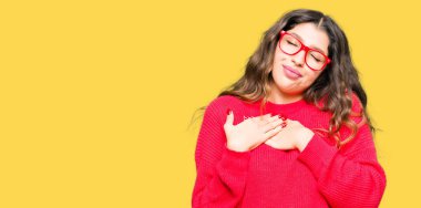 Kırmızı gözlük ile gülümseyen genç güzel kadın kapalı gözler ve yüzünde minnettar jest ile göğüs üzerinde eller. Sağlık kavramı.