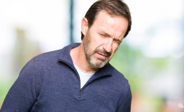 Orta yaş yakışıklı adam çünkü mide üzerinde el ile kazak giyen mide bulantısı, ağrılı hastalık hasta hissediyor. Ağrısı kavramı.