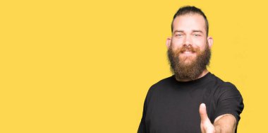 Genç sarışın adam rahat t-shirt giyen tebrik ve karşılama olarak el sıkışma sunan dostu gülümseyerek. Başarılı iş.