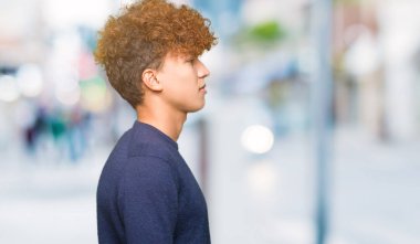 Genç yakışıklı adam ile afro saç arıyor yan, dinlenmek profil poz doğal yüz ile emin gülümseme.