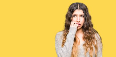 Stresli ve gergin elle çivi ısırma ağzına bakarak kış elbise giyen genç güzel kadın. Anksiyete sorunu.