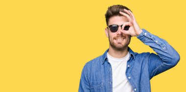 Gülümseyen, parmakları ile mutlu yüz üzerinden seyir göz el ile ok jest yapıyor Kot ceket giyen genç yakışıklı zarif adam.