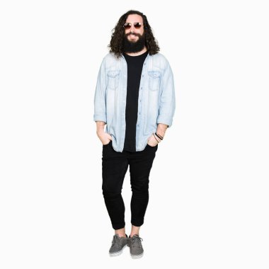 Genç hipster adamla uzun saç ve sakal uzak tarafına yüzünde, doğal ifade gülümseme ile seyir güneş gözlüğü takıyor. Kendine güvenen gülüyor.
