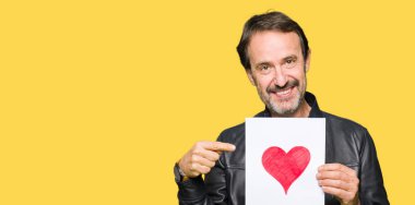 Kağıt kırmızı kalp ile çok mutlu el ve parmak ile işaret tutan yakışıklı orta yaş erkek