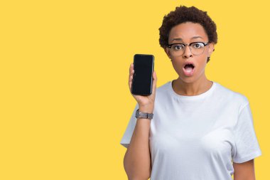Genç Afro-Amerikan kadın gösteren smartphone ekran izole arka şok sürpriz yüzü, korkuyor ve korku ifadesi ile heyecanlı olan korkmuş üzerinde