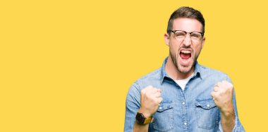 Yakışıklı adam çok mutlu ve heyecanlı silah ile kazanan jest yaparken gözlük giyiyor, gülümseyen ve başarı için çığlık kaldırdı. Kutlama konsepti.