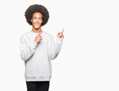 Afro saçlı genç afro-amerikan adam sportif sweatshirt gülümseyerek ve yan iki el ve parmakları ile işaret kamera bakıyor.