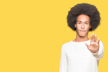 Stop yapıyor kış kazak giyen afro saçlı genç Afro-Amerikan adam elin avuç ile şarkı. Negatif ve ciddi bir jest yüz ifadesiyle uyarı.