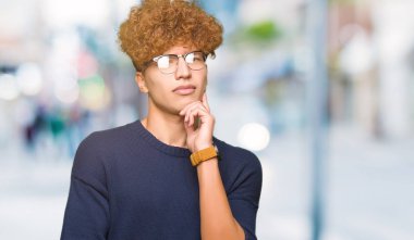 Yakışıklı delikanlı ile gözlük el ile çene düşünme hakkında soru, dalgın ifade üzerine afro. Düşünceli yüzüyle gülümsüyor. Şüphe kavramı.