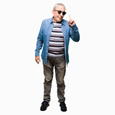 Yakışıklı kıdemli dostum giyen denim ceket ve güneş gözlüğü ile başarılı fikir parmak işaret. Çıktıktan ve mutlu. Bir numara.