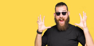 Genç hipster adam deli ve silah ile başarı için hayran kutluyor güneş gözlüğü takıyor kaldırdı ve açık gözleri çığlık heyecanlı. Kazanan kavramı