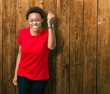 Güzel genç Afro-Amerikan kadın üzerinde gözlük takan arka plan kızgın izole ve kızgın yetiştirme hayal kırıklığı ve öfke ile bağırarak süre öfkeli yumruk. Öfke ve agresif kavramı.