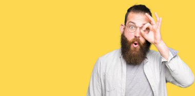 Gözlük takan genç sarışın adam ok jesti yaparak şaşkın yüzüyle şoke oldu, göz lerinden parmaklarından bakıyor. İnanmayan ifade.