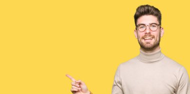 Kameraya bakarak yan el ve parmak ile işaret yüzünde, kocaman bir gülümseme ile gözlük takan genç yakışıklı iş adamı.