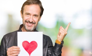 Kağıt kırmızı kalp ile çok mutlu el ve parmak ile tarafına işaret tutan yakışıklı orta yaş erkek
