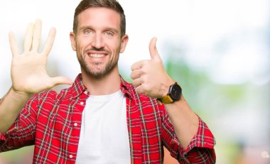 Yakışıklı adam rahat gömlek gösteren giyen ve parmakları ile işaret ederken kendinden emin ve mutlu gülümsüyor.