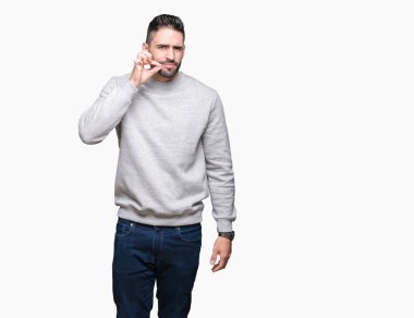 Üzerinde sweatshirt giyen genç yakışıklı adam arka plan ağız izole ve parmak ile ZIP olarak Dudaklarını kapa. Gizli ve sessiz, tabu söz