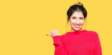 Kırmızı kazak ve çörek arıyorum ve başparmak yanında yukarıyı mutlu yüz ile gülümseyen giyen genç güzel kadın.