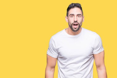 İzole arka plan korkuyor ve şok sürpriz ifade, korku ve heyecan yüz üzerinden Casual beyaz t-shirt giyen genç adam.