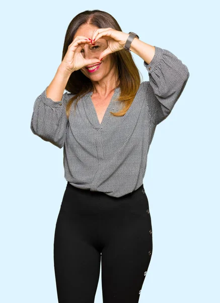 Güzel orta yaş iş kadını yapıyor kalp şekli ile el ve parmak işareti seyir gülümseyen