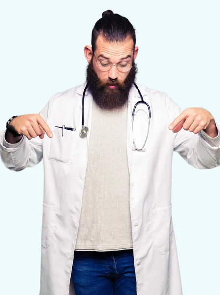 ひげ医療身に着けている若いブロンド医師男表示広告 驚いた顔 口を開けて指をポインティングをコートします — ストック写真