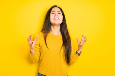 Güzel esmer kadın yüzünden sarı arka plan deli izole ve deli bağırarak ve agresif ifade ve silah kaldırdı bağırıyor. Hayal kırıklığı kavramı.