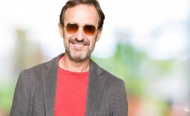 Orta Çağ yakışıklı iş adamı yüzünde mutlu ve serin bir gülümseme ile güneş gözlüğü giyiyor. Şanslı kişi.