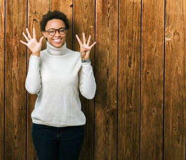Genç güzel Afrikalı-Amerikalı kadın gözlük gösterilen ve parmakları ile işaret izole arka plan üzerinde dokuz kendinden emin ve mutlu gülümseyerek iken numara.