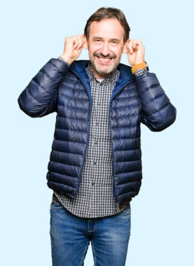 Orta Çağ yakışıklı adam kış ceket giyiyor parmaklar, komik jest ile kulakları çekerek gülümsüyor. Audition sorunu