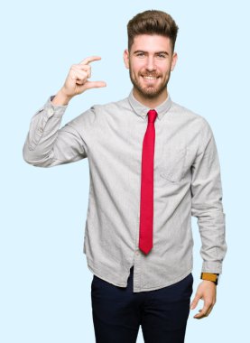 Gülümseyen genç yakışıklı iş adamı ve süre seyir ve kamera boyutu işaret parmaklarıyla yapıyor el ile kendine güvenen el hareketi. Ölçü kavramı.